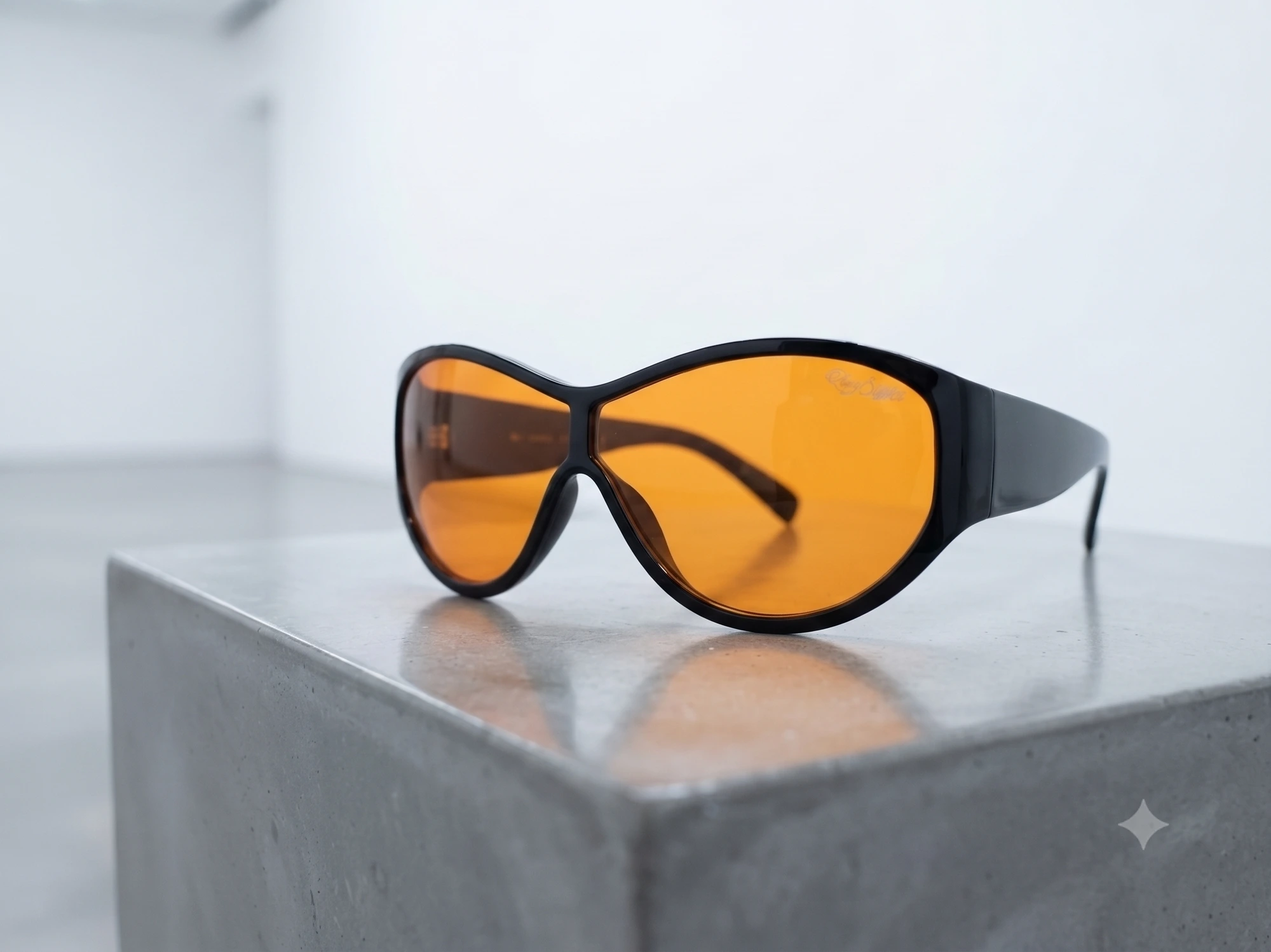 RayStance Ember — black sunglasses with orange lenses on concrete